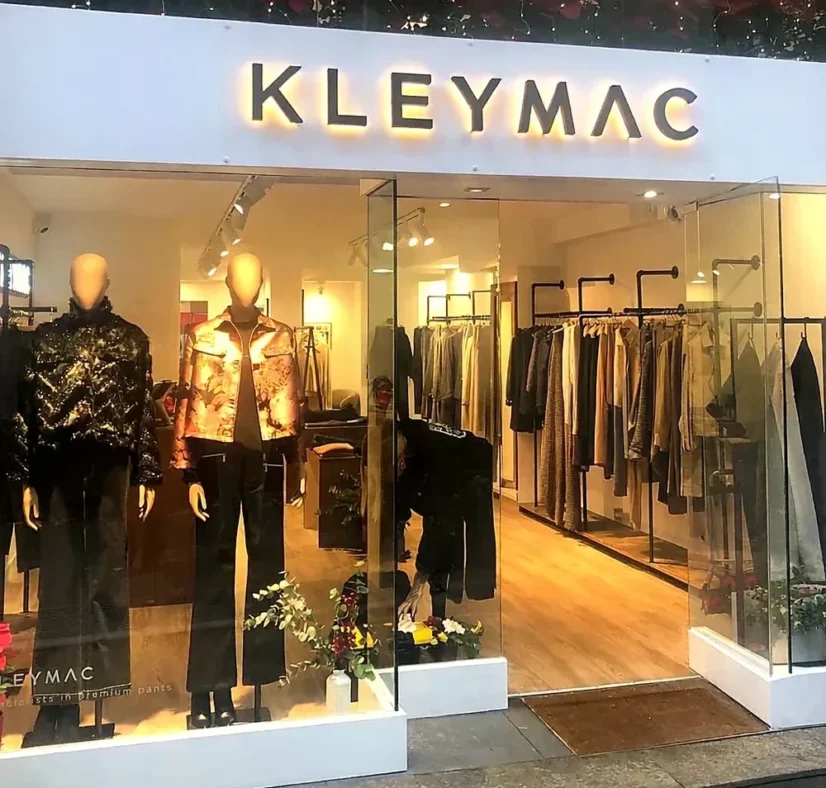 tienda de ropa perchero de hierro y madera mostrador y rotulos